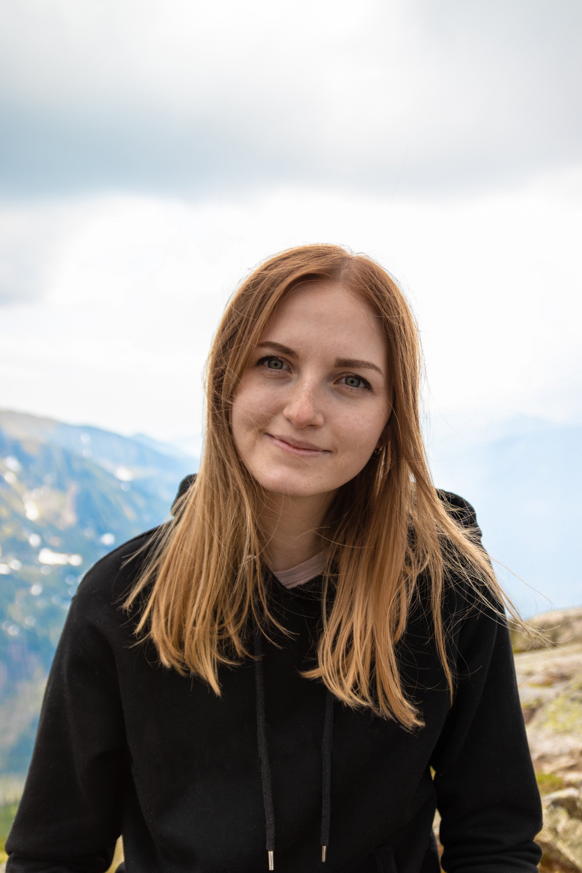 files/young-blonde-girl-traveler-with-blue-backpack-raised-enjoying-green-mountain-scenery.jpg